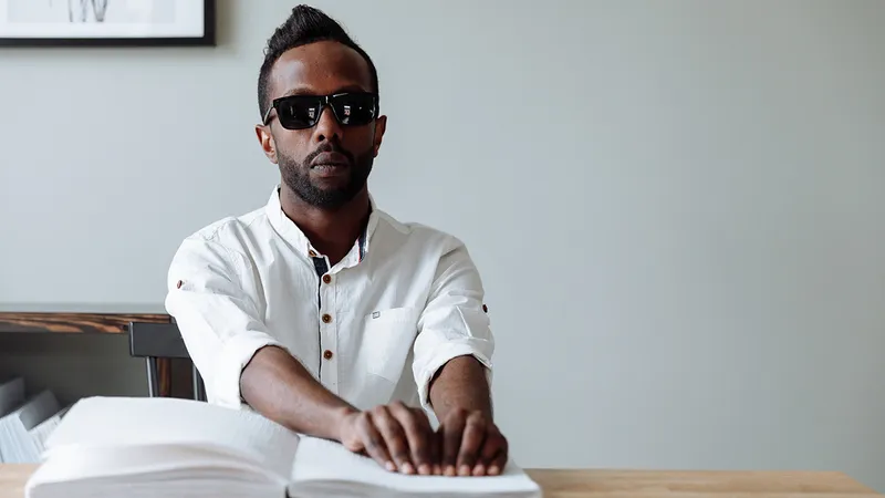 Man sits at a desk and reads braille.
