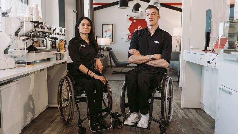 Two people in wheelchairs in a company kitchen