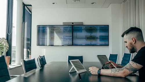 A Daniel Wellington staff member in a conference room uses his Jamf-managed iPad.
