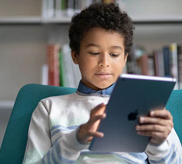 Child in a school library works on an iPad filtered by Jamf Safe Internet.