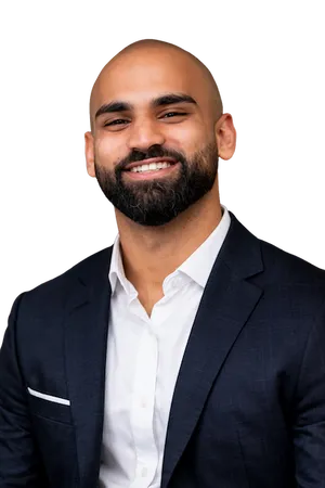 Professional headshot of Saket Lingala smiling, wearing a navy blazer and white shirt on white background